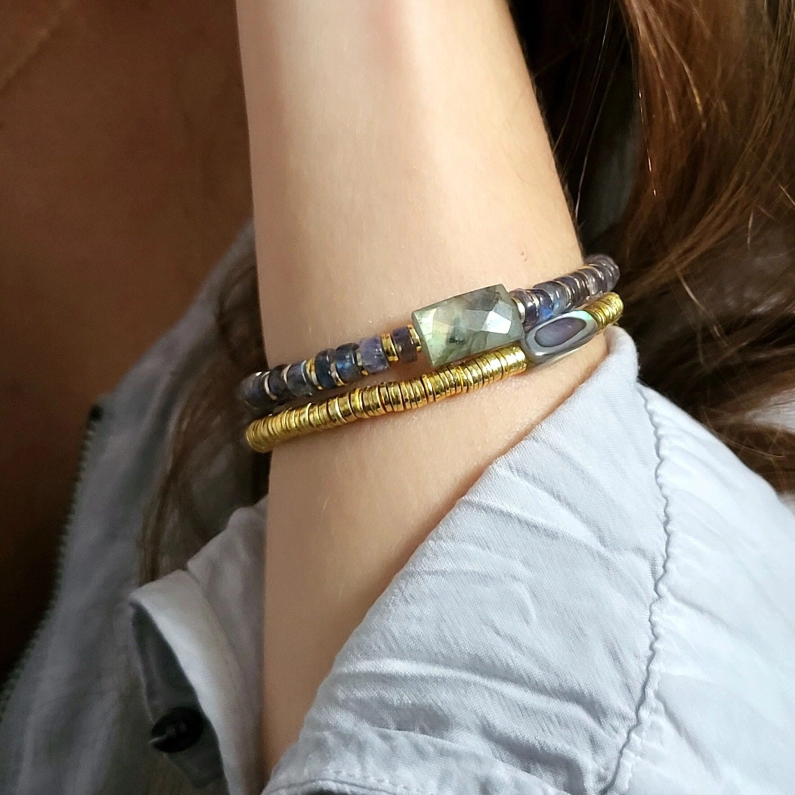 Lila-in-the-sky-armband-aurore-labradorit-2 Frauenarm mit Armband aus Labradorit Edelsteinen in verschiedenen Farben und Golddetails