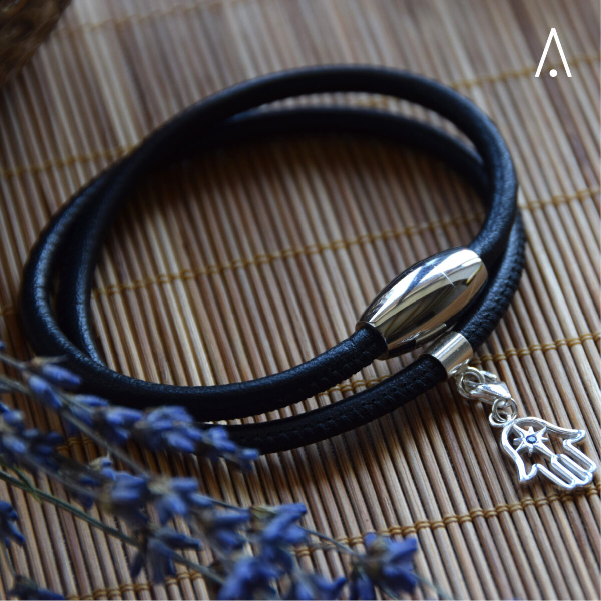 Schwarzes Lederarmband zweifach gewickelt mit Magnetverschluss und Hamsa Charm Anhänger. Dekoriert mit Lavendelblüten